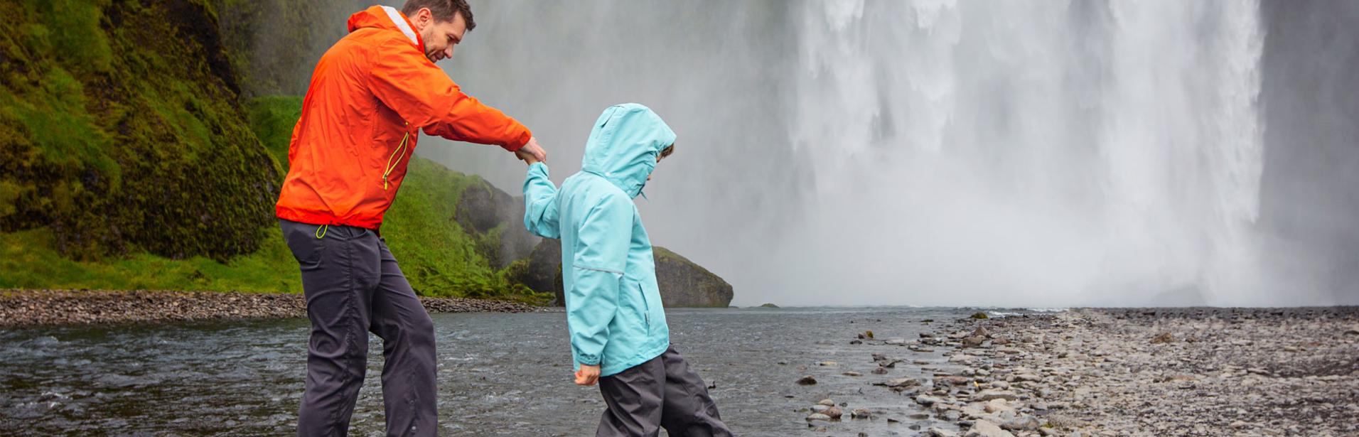 Far och son besöker vattenfallet Skogafoss på Island.