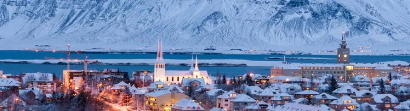 Snötäckt Reykjavík med berg i bakgrunden.