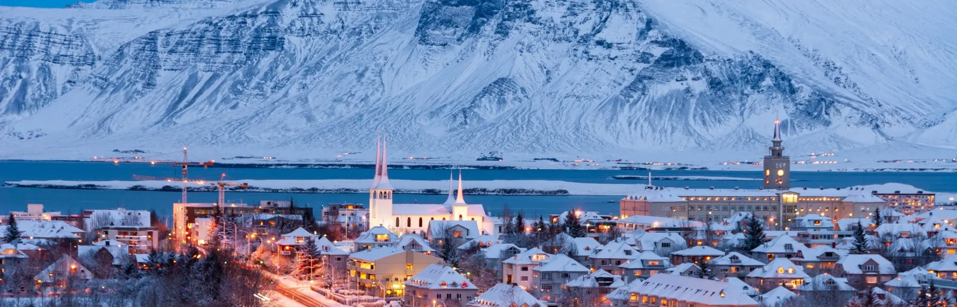 Snötäckt Reykjavík med berg i bakgrunden.