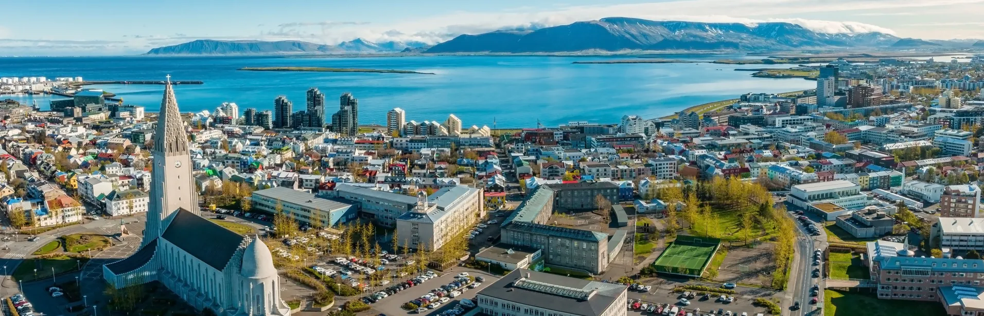 Vy över Reykjavík med Hallgrímskirkja, havet och bergen i bakgrunden.