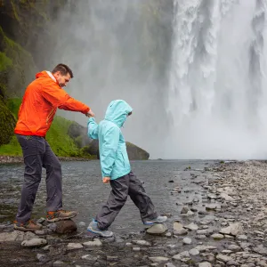 Far och son besöker vattenfallet Skogafoss på Island.